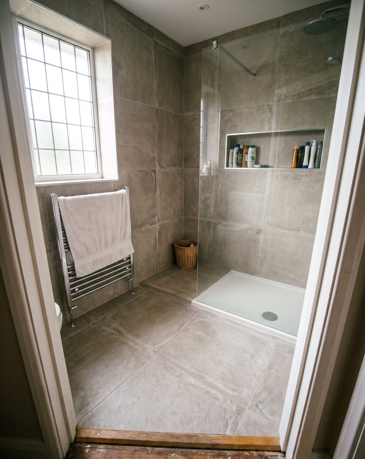 A newly tiled bathroom with large grey porcelain tiles and a walk-in shower